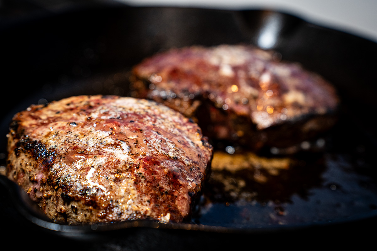 Two Steaks Sizzling in a Pan